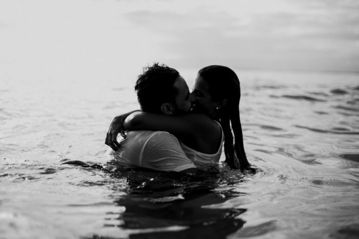 a man and a woman are kissing on the water